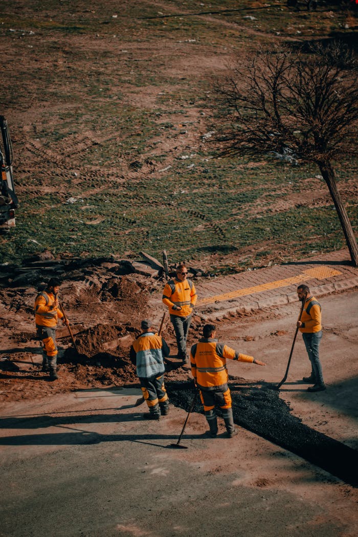 Group of road workers repairing asphalt in Kayseri, Turkey, in a sunny outdoor setting.
