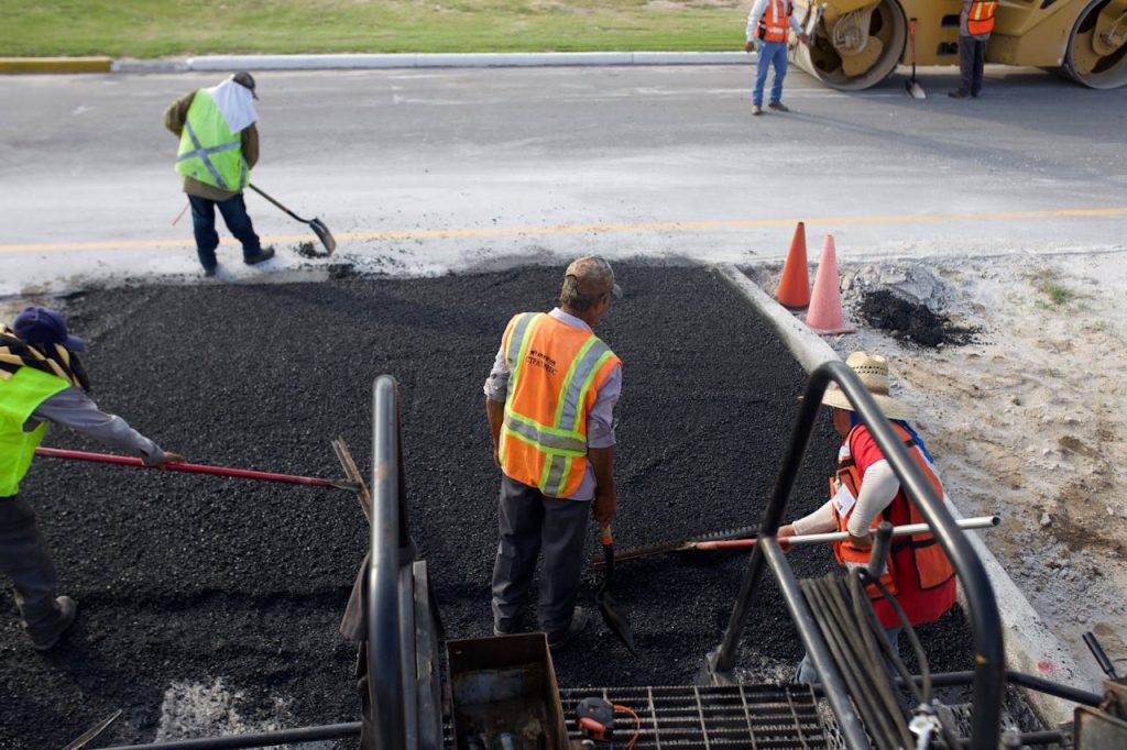 Group of road construction workers laying fresh asphalt outdoors during the day.